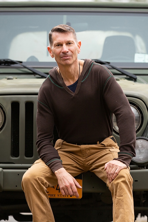 Man sitting on the bumper of a green Jeep