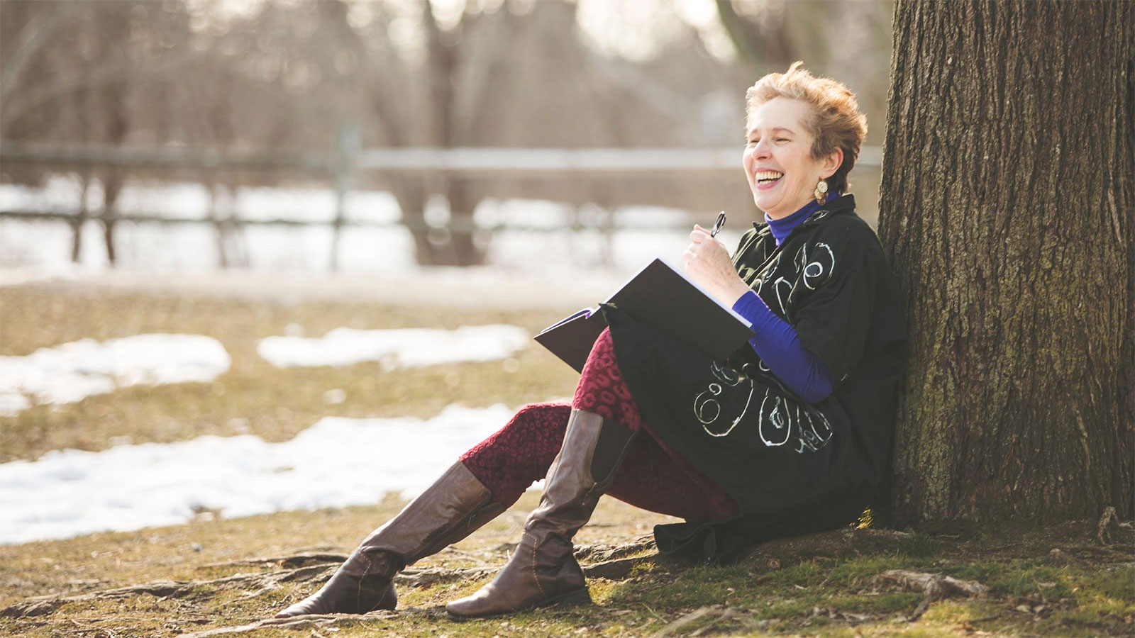 Women sitting by a tree with her journal, laughing